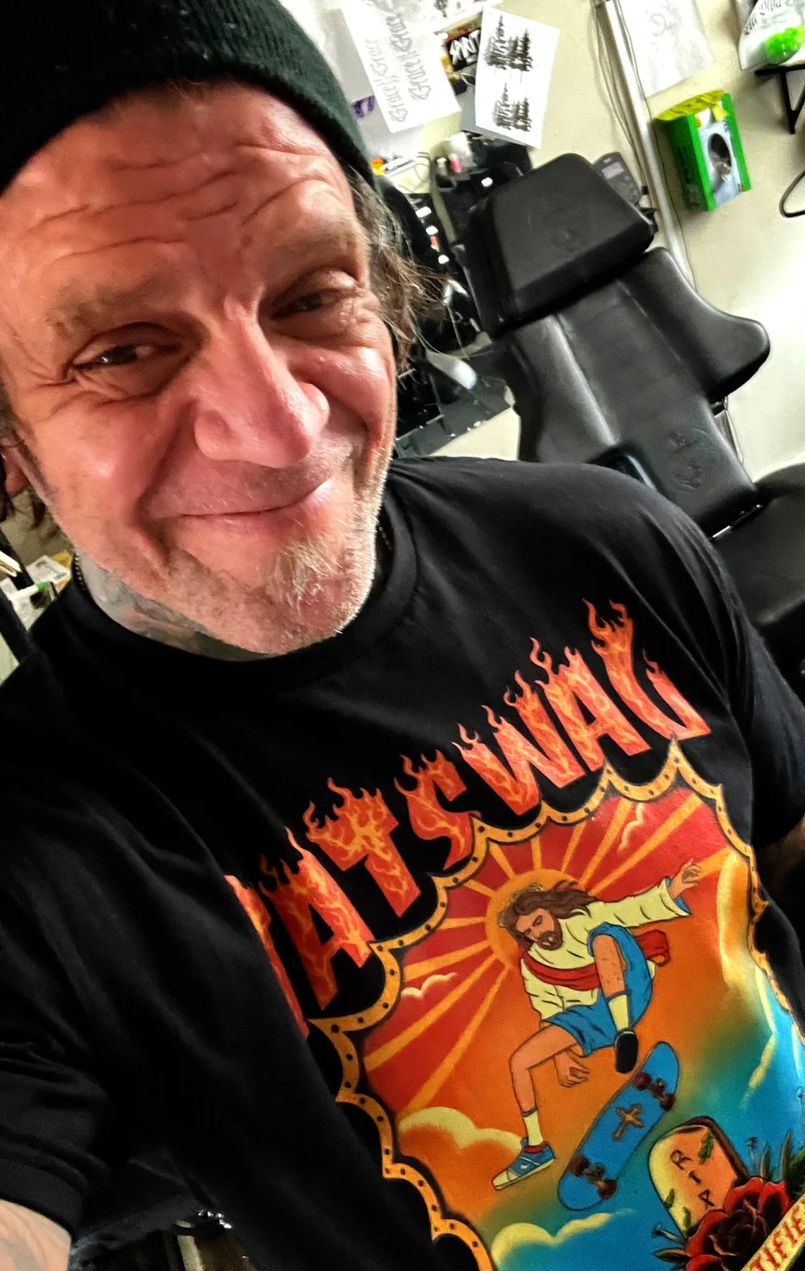 At the tattoo studio, wearing a black illustrated skate shirt
